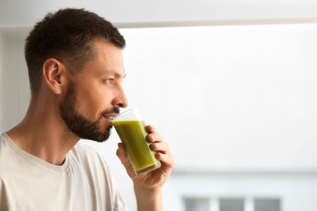 Man drinking delicious juice indoors, space for text