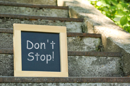 Chalkboard with phrase Don't Stop on stone stairs outdoors, space for textの写真素材