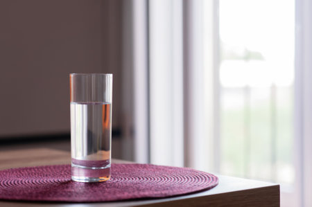 Glass of water on wooden table in the room. Space for text