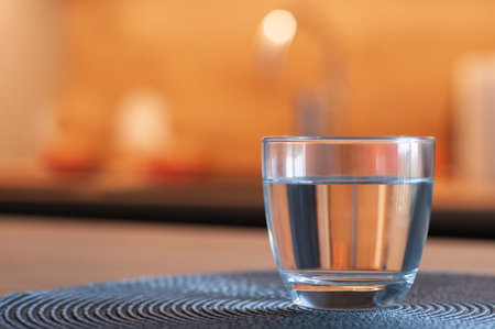 Glass of water on table against blurred background, closeup. Space for textの写真素材