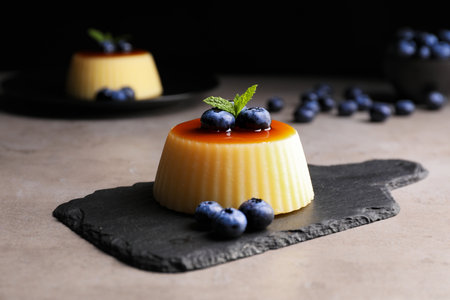Delicious caramel pudding with blueberries and mint on gray tableの写真素材