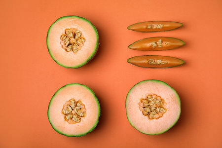 Cut different types of melons on orange background, flat layの写真素材