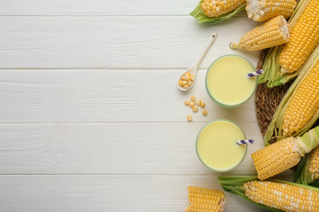 Corn juice and cobs on white wooden table, flat lay. Space for textの写真素材