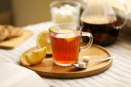 Glass mug of aromatic tea with lemon and sugar on tableの写真素材