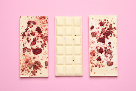 White chocolate bars with freeze dried fruits on pink background, flat layの写真素材