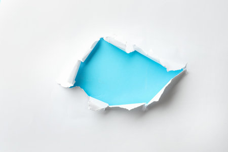 Hole in white paper on light blue backgroundの写真素材