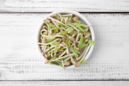 Mung bean sprouts in bowl on white wooden table, top viewの写真素材
