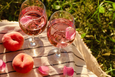 Glasses of delicious rose with petals wine and peaches on white picnic blanket outside, above viewの写真素材
