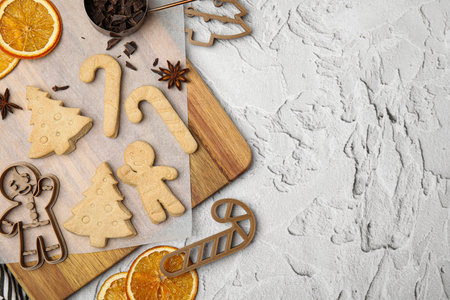 Christmas treat. Flat lay composition with cookie cutters and baked biscuits on white textured...