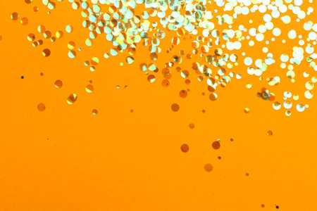 Shiny bright glitter on orange background, flat layの写真素材