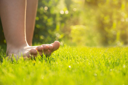 Teenage girl walking barefoot on green grass outdoors, closeup. Space for textの写真素材