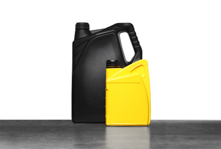 Motor oil in different containers on gray table against white background