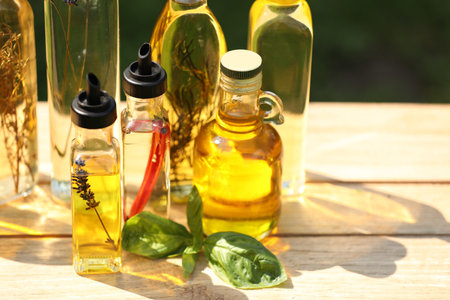 Many different cooking oils on wooden table against blurred green background, closeup. Space for textの写真素材