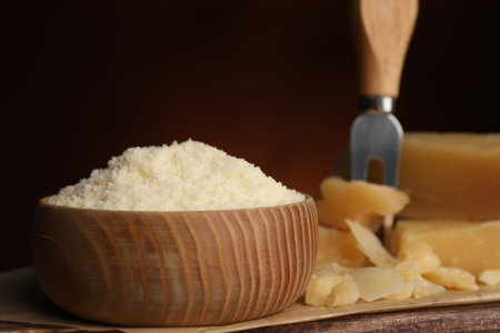 Delicious grated parmesan cheese in bowl on wooden tableの写真素材