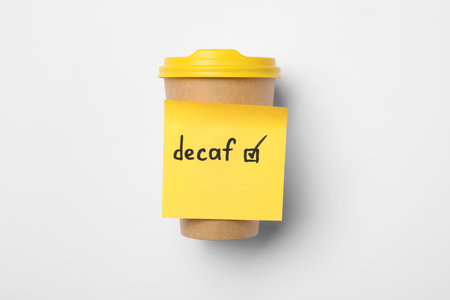 Note with word Decaf and checkbox attached to takeaway coffee cup on white background, top viewの写真素材