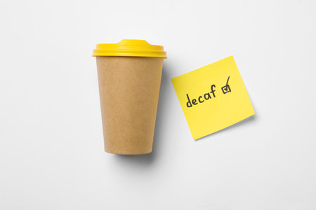 Takeaway coffe cup, note with word Decaf and checkbox on white background, flat layの写真素材