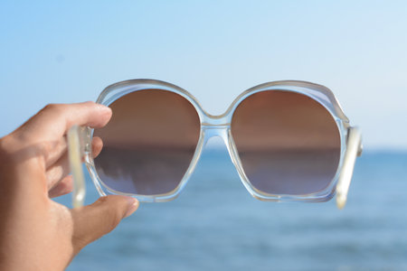 Woman holding stylish sunglasses near sea, closeupの写真素材