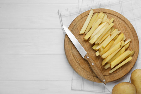 Cut raw potatoes on white wooden table, top view. Space for textの写真素材