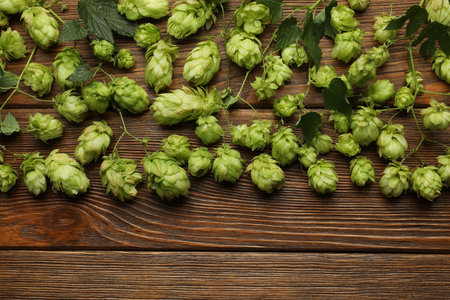 Branches of fresh green hops on wooden table, flat lay. Space for text