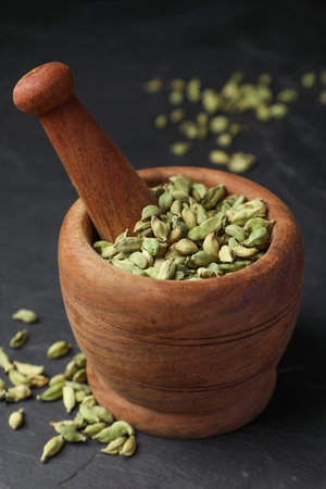 Mortar with pestle and dry cardamom pods on dark gray table, closeupの写真素材
