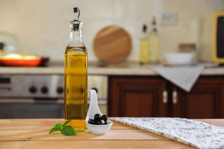 Bottle of cooking oil, olives and basil on wooden table in kitchen, space for textの写真素材