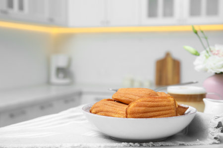 Tasty madeleine cookies on table in kitchen, space for text