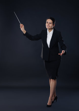 Happy young conductor with baton on dark backgroundの写真素材