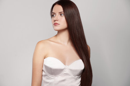 Portrait of beautiful young woman with healthy strong hair on light gray backgroundの写真素材