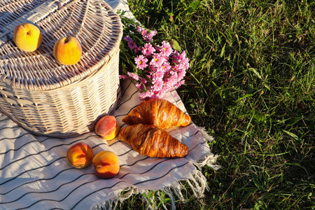 Picnic basket, flowers and food on blanket outdoorsの写真素材