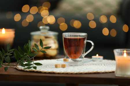 Tea, cookies and decorative elements on wooden table against blurred lights indoorsの写真素材