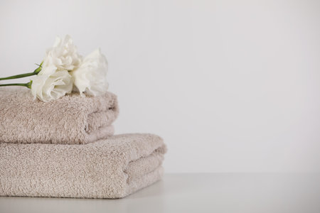 Soft folded towels and eustoma flowers on white table, space for textの写真素材