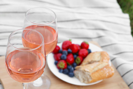 Glasses of delicious rose wine and food on white picnic blanket, closeupの写真素材