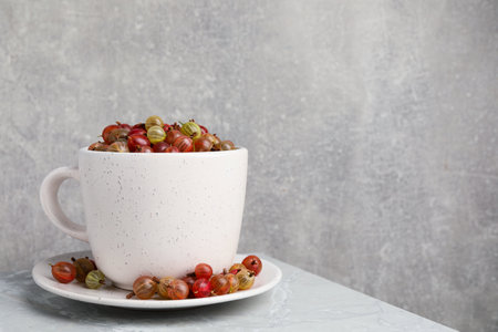 Cup with ripe gooseberries on light gray marble table, space for textの写真素材