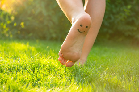 Teenage girl with smiling face drawn on heel walking outdoors, closeupの写真素材