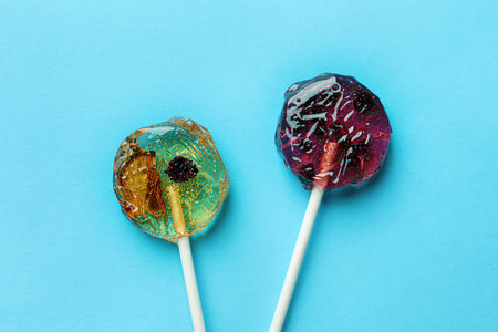 Sweet colorful lollipops with berries on light blue background, flat layの写真素材