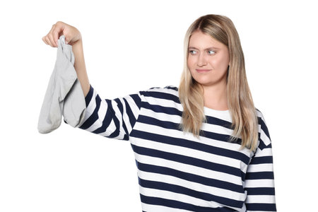 Young woman feeling bad smell from dirty socks isolated on whiteの写真素材