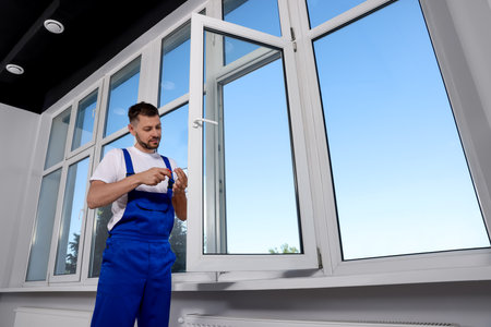 Construction worker adjusting installed window with screwdriver indoorsの写真素材