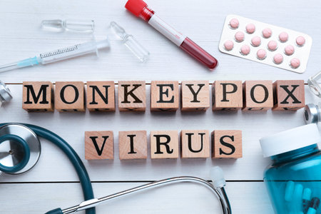 Flat lay composition with words Monkeypox Virus made of cubes and medical supplies on wooden white...
