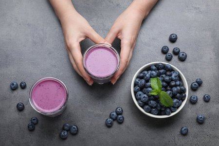 Woman with tasty blueberry smoothie on gray table, top viewの写真素材