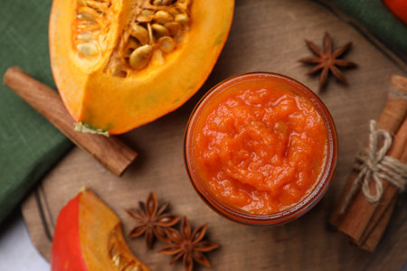 Jar of delicious pumpkin jam and ingredients on wooden board, flat layの写真素材
