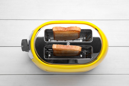 Yellow toaster with roasted bread on white wooden table, top viewの写真素材