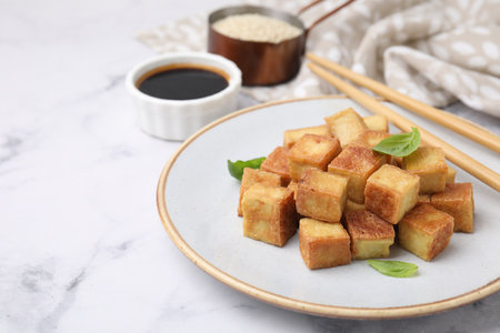 Delicious fried tofu with basil served on white marble table, closeup. Space for textの写真素材