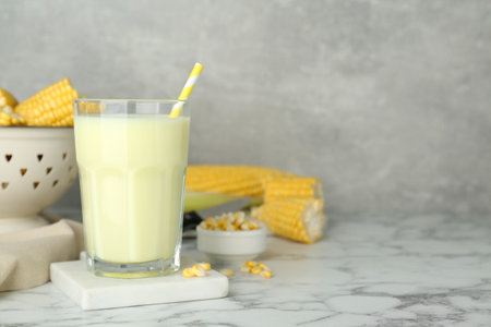 Tasty fresh corn milk in glass on white marble table. Space for textの写真素材