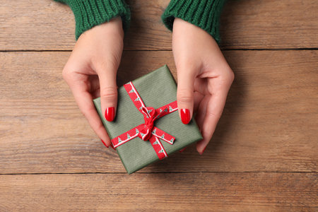 Christmas present. Woman with gift box at wooden table, top viewの写真素材