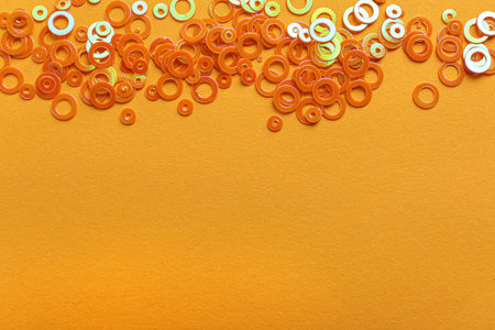 Shiny bright glitter on light orange background, flat lay. Space for textの写真素材