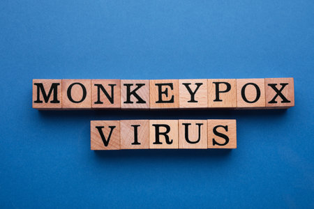 Words Monkeypox Virus made of wooden cubes on blue background, flat lay