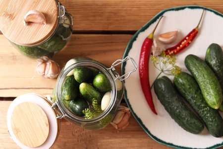 Fresh cucumbers, garlic and pepper on wooden table, flat lay. pickling recipeの写真素材