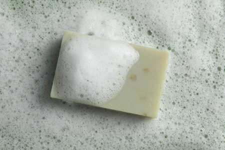 Soap and fluffy foam on green background, top viewの写真素材