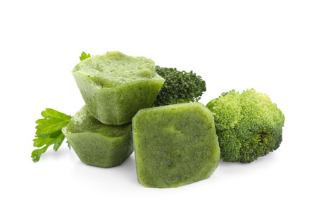 Frozen broccoli puree cubes and fresh broccoli isolated on whiteの写真素材
