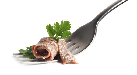 Fork with delicious anchovy fillet and parsley isolated on whiteの写真素材
